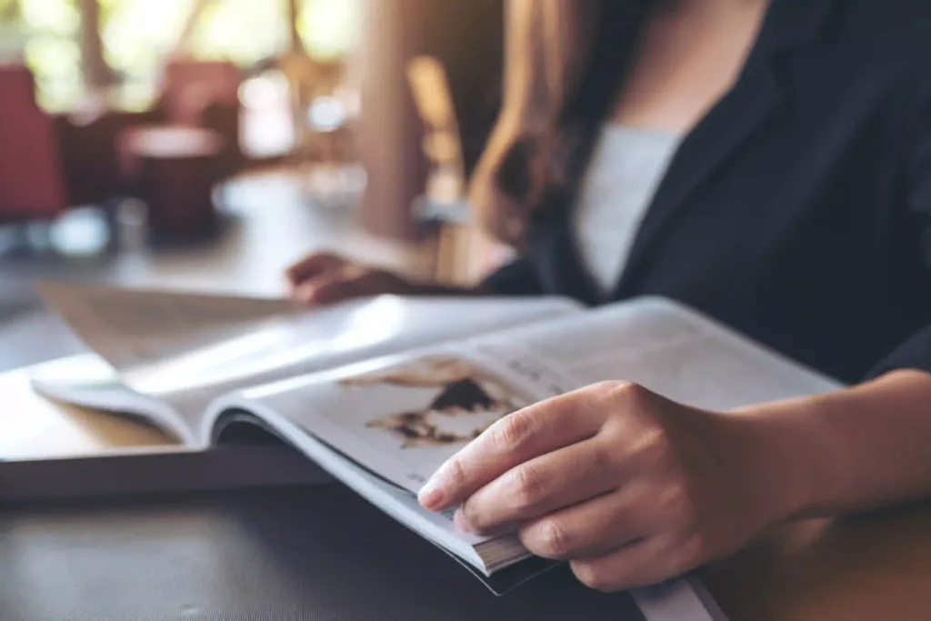 Closeup image of a business woman reading a softcover book in modern cafe