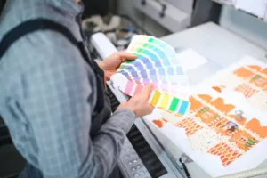 Print House Worker Controlling Printing Process Quality And Checking Colors With Magnifying Glass